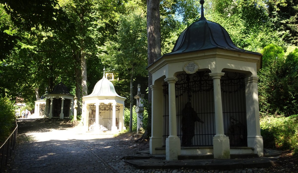 Stationen des Kreuzweges hinauf zur Felsenkapelle St. Salvator umrahmt von grünen Bäumen., © Foto: Cornelia Steinbach