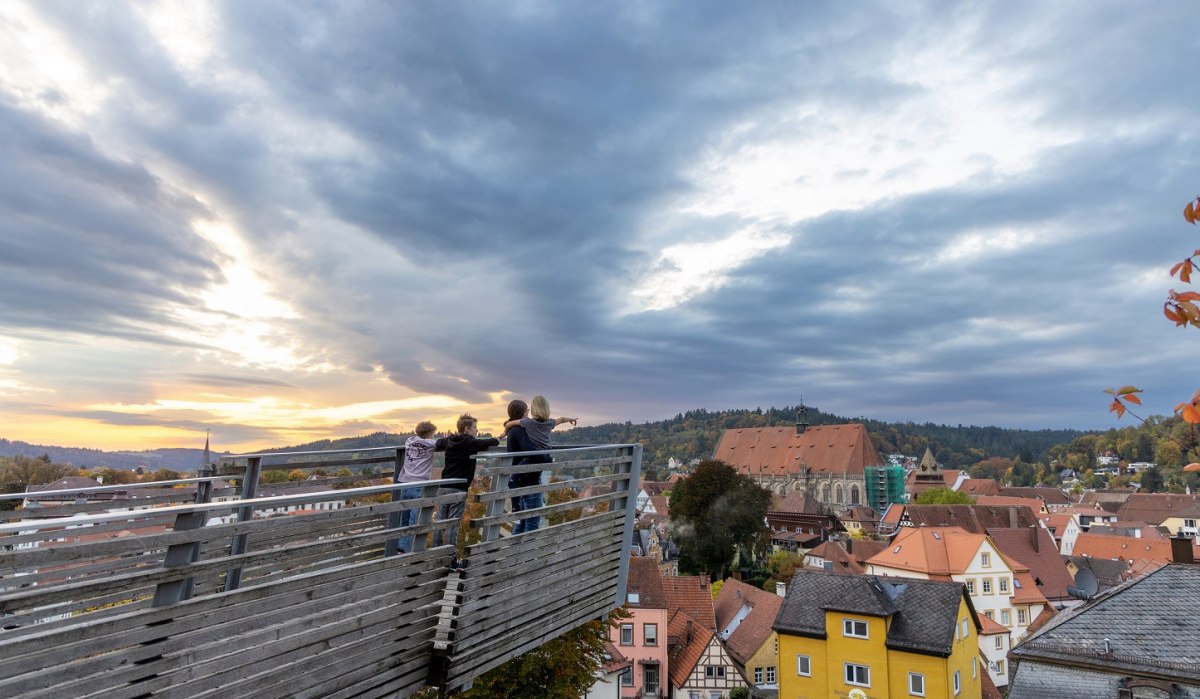 Auf der aus Holz verkleideten Aussichtsplattform stehen zwei Jungen und eine Frau die ein Mädchen auf dem Arm hat. Der Himmel ist wolkig, aber die Sonne scheint an einzelnen Stellen durch. Der Blick zeigt Schwäbisch Gmünd von oben. Gut erkennbar ist das Heilig-Kreuz-Münster., © Foto: Thomas Zehnder