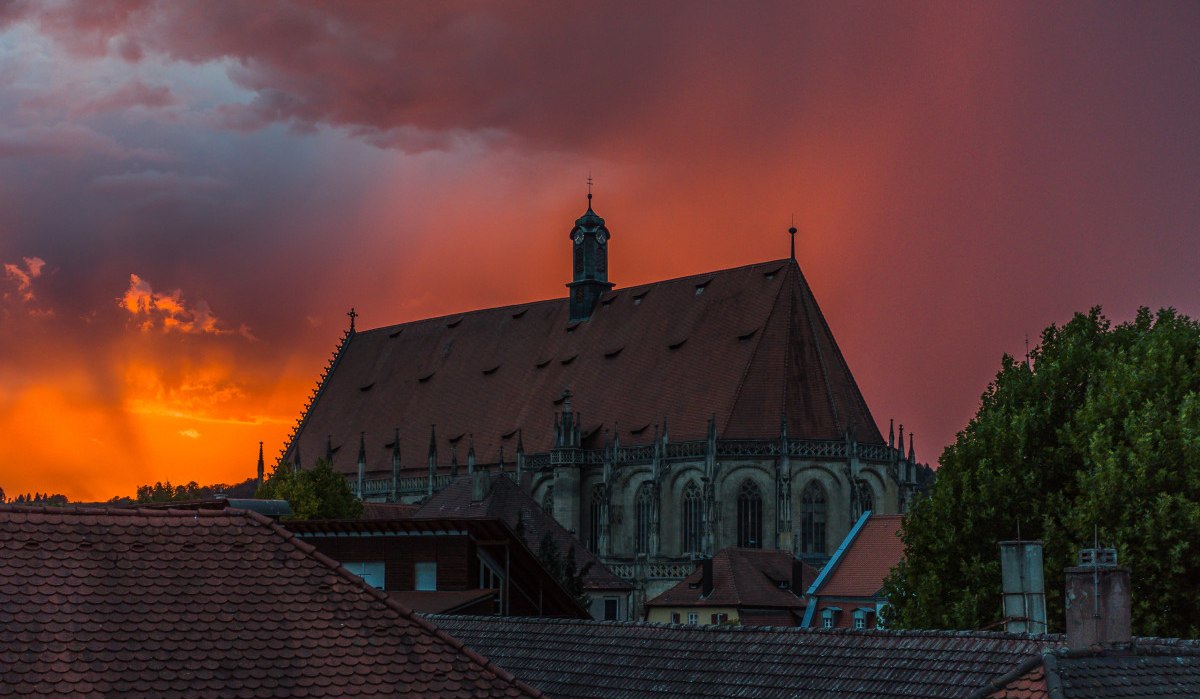 Die Kirche Heilig-Kreuz-Münster bei Sonnenuntergang. Der Himmel ist orange rot., © Foto: Mario Klaiber